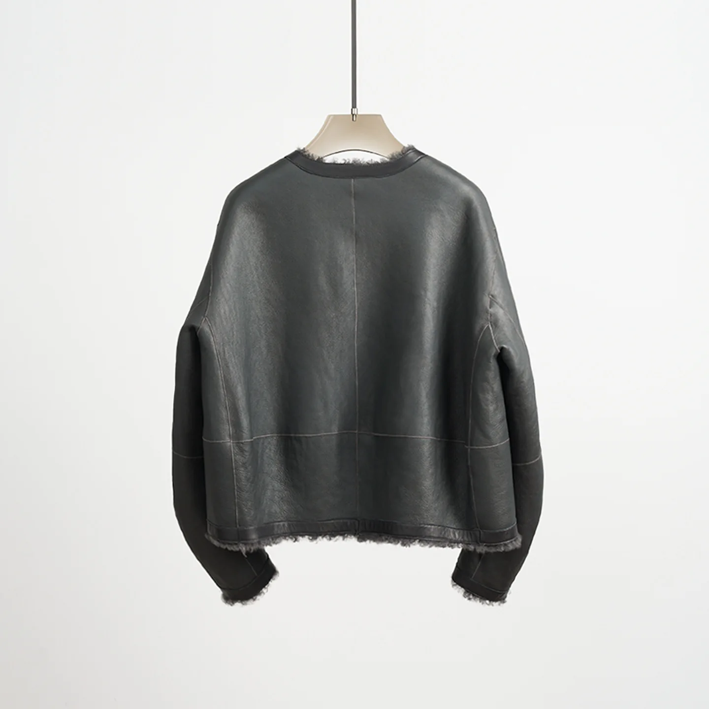 Abrigo de piel reversible recortado y holgado con cuello redondo de punto de lana y piel de oveja de primera calidad ultra minimalista