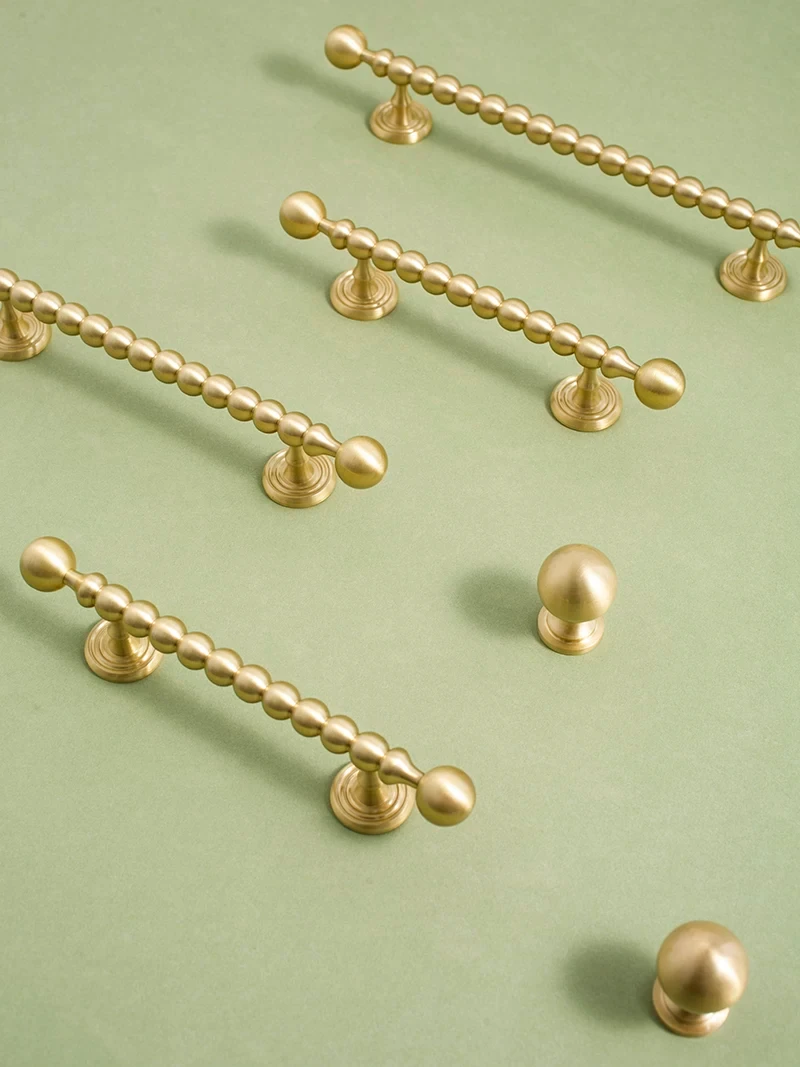 Beaded drawer pulls and round brass knobs displayed together