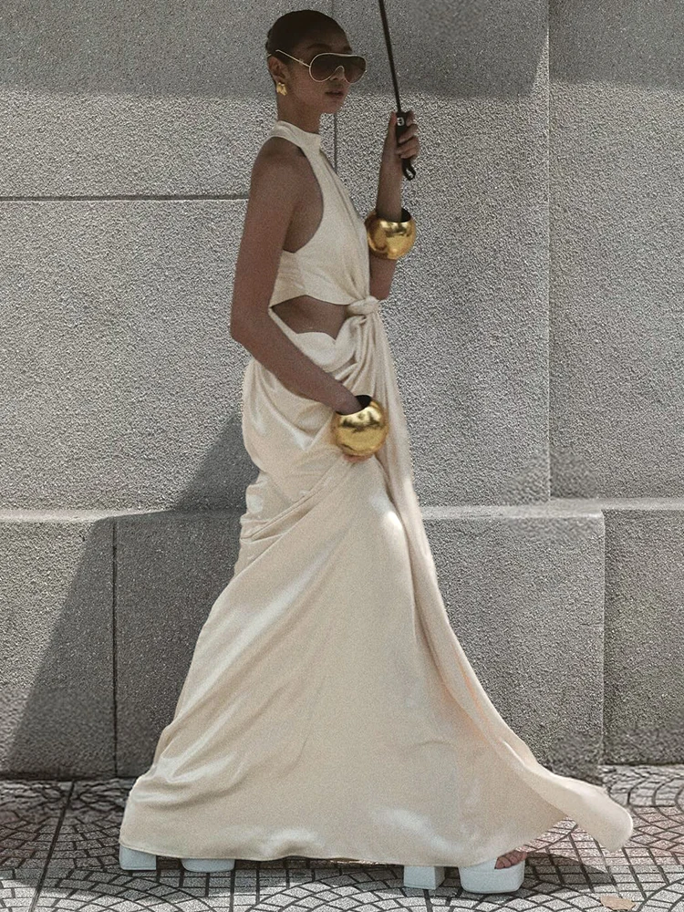 Elegancka, seksowna suknia wieczorowa bez rękawów w kolorze beżowym, z dekoltem typu halter, drapowaniem i wycięciem, idealna na bal maturalny lub przyjęcie koktajlowe.