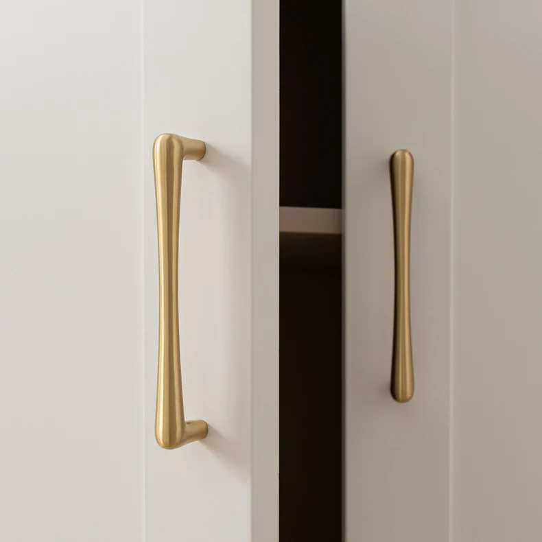 Brass handle fitted vertically to a white cupboard door