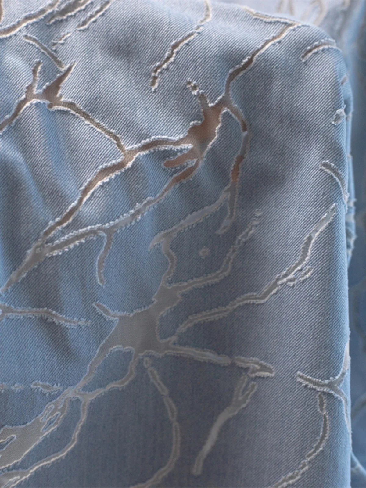 Tela vaquera azul y blanca con diseño floral quemado, transformación de malla hueca con efecto craquelado, transparente, creativa y de diseño.