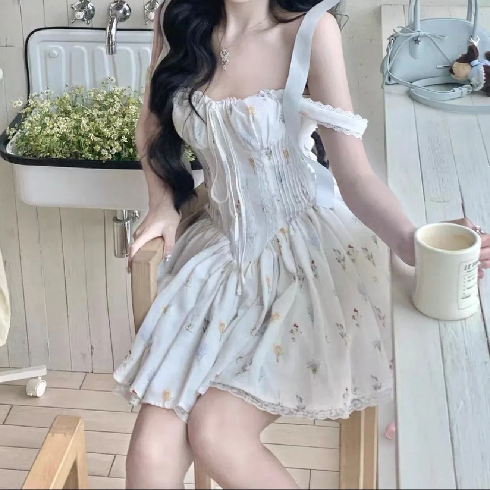 甘い花柄プリントとレースを組み合わせた、胸元にギャザーが入ったミニ丈のスリングドレス。女性用、クロスバックで紐を結ぶ、ローウエストのAラインスイングタンクドレス。
