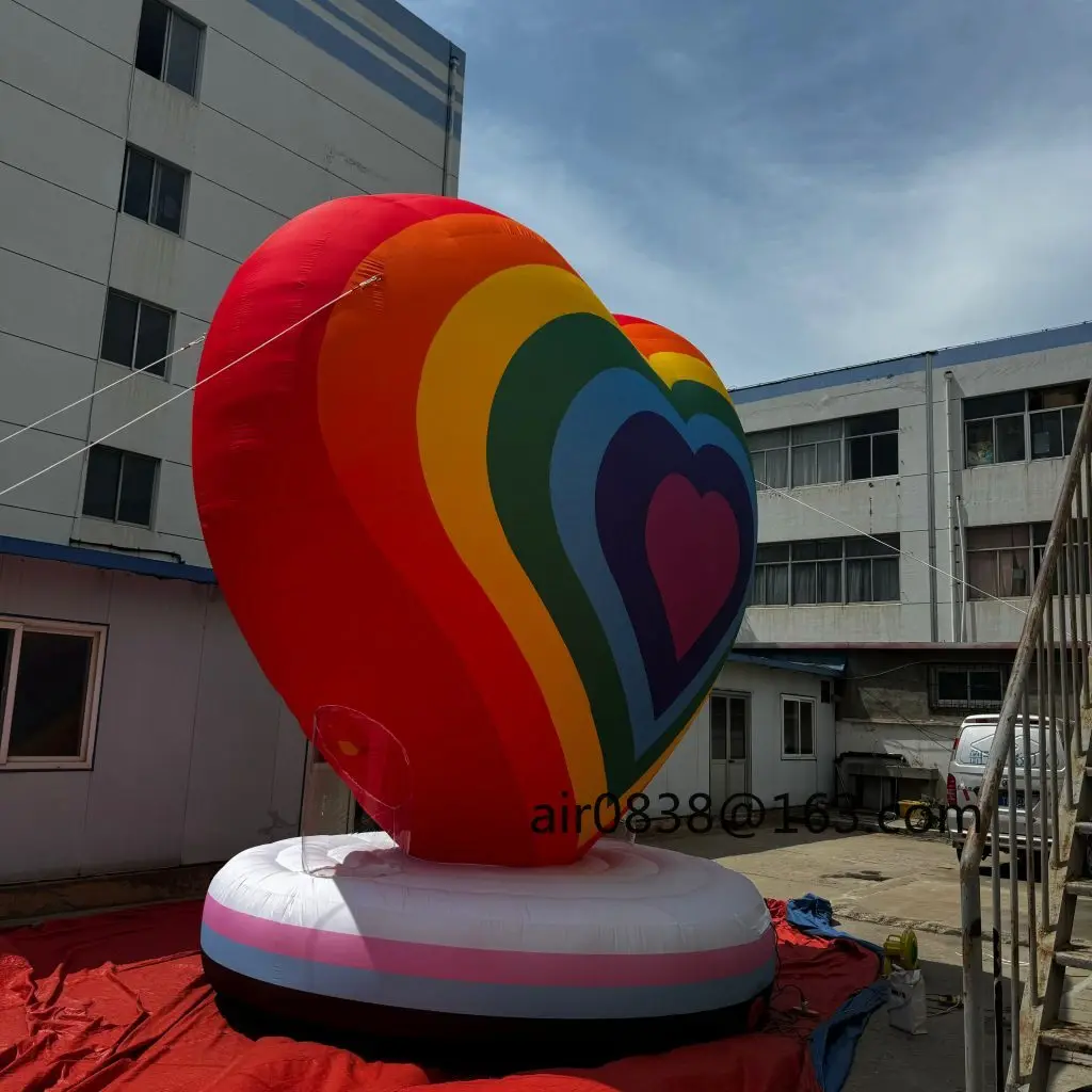 カラフルな虹色の膨らませるハート型、丸い台座付き巨大な膨らませるハート型モデル、結婚式パーティーイベントの装飾に
