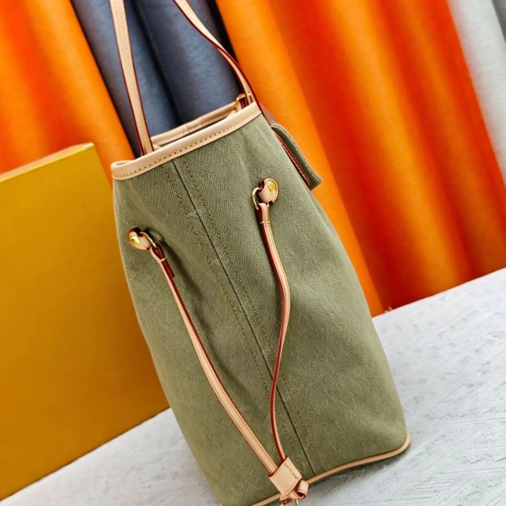 Olive green canvas tote bag with natural leather trim, adjustable drawstring sides and detachable shoulder strap.