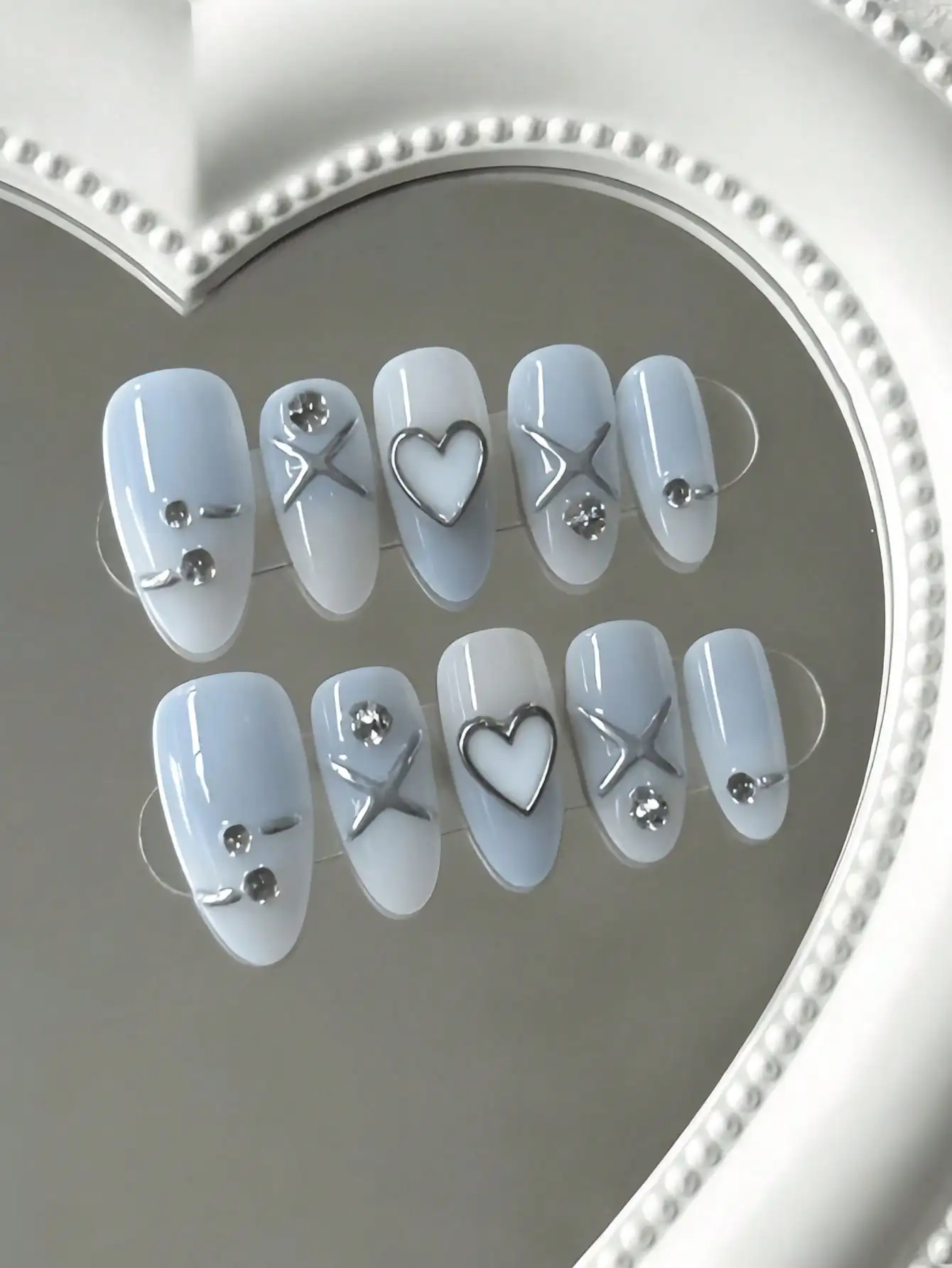 10 faux ongles en forme d'amande, de longueur moyenne, bleus et blancs, en forme de cœur et d'étoile, style cool et doux, avec des motifs en cœurs 3D, étoiles croisées et strass métalliques, couleur nude et couleurs contrastées, techniques de décoration 3D, adaptés aux jeunes filles et jeunes femmes, parfaits pour les trajets quotidiens, les rendez-vous élégants et les sorties tendance, livrés avec colle gel et lime à ongles.