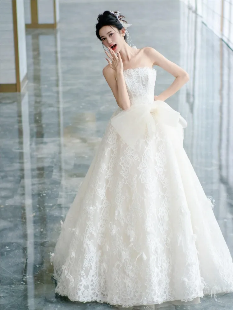 The strapless light wedding dress features a with forest-themed lace tail