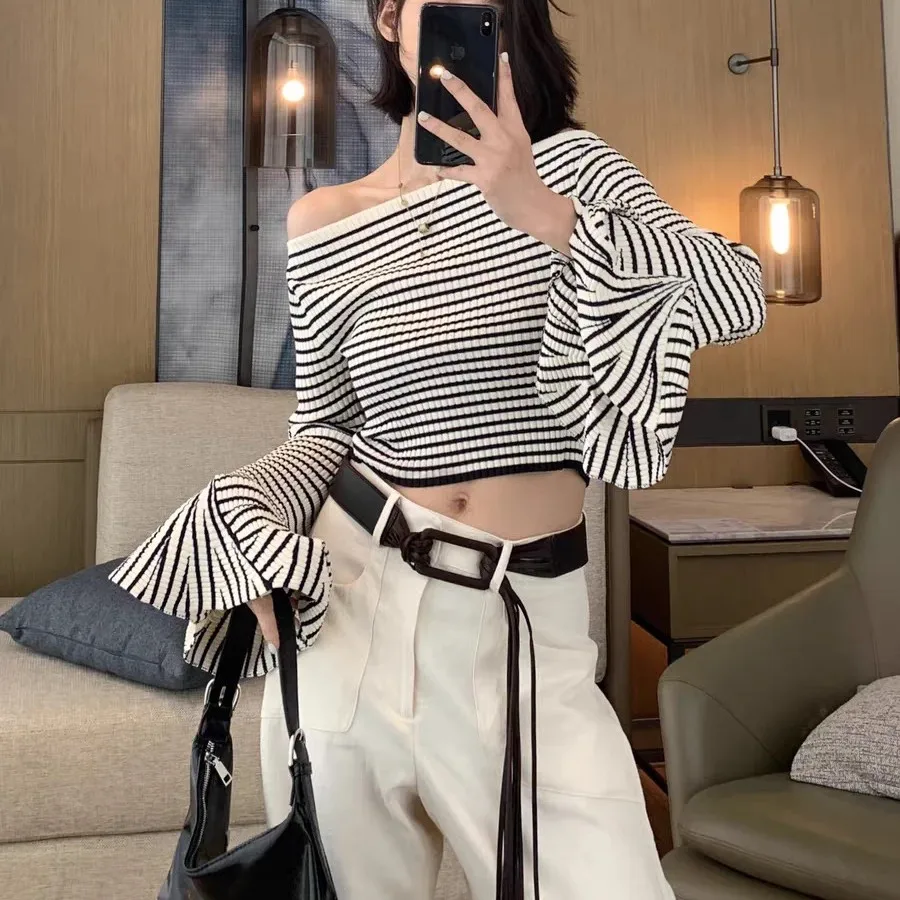 เสื้อถักไหมพรมสไตล์ยุโรประดับไฮเอนด์ ดีไซน์เปิดไหล่ข้างเดียว ลายทางสีขาวดำ แขนทรงกระดิ่ง ช่วงเอวไม่สมมาตร สำหรับผู้หญิง...