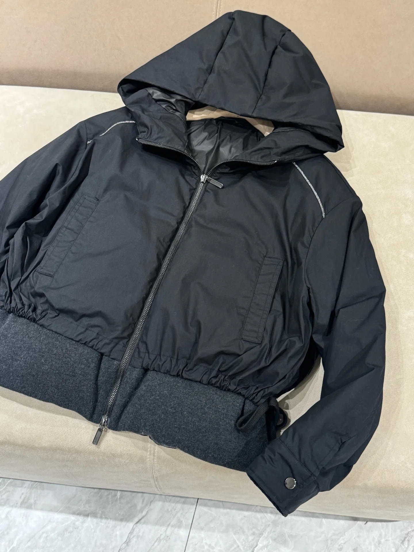 เสื้อแจ็คเก็ตขนเป็ดผสมแคชเมียร์ ขนสัตว์ และผ้าไหม พร้อมฮู้ด แต่งโซ่ประดับลูกปัด และแขนเสื้อแบบดรอปชอลเดอร์ เพื่อทรงสวยสง่า