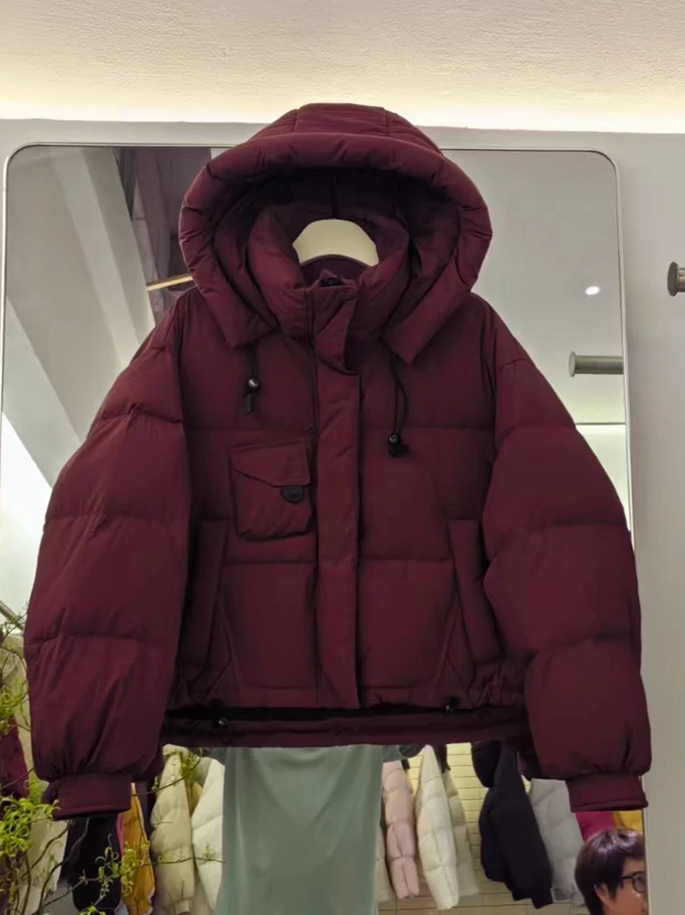 เสื้อแจ็คเก็ตขนเป็ดสำหรับผู้หญิง รุ่นใหม่ ปี 2025 ฤดูหนาว แบบสั้นมีฮู้ด สไตล์เกาหลี หนา ทรงขนมปัง อเนกประสงค์ ขนเป็ดขาว  เสื้อโค้ทแฟชั่น