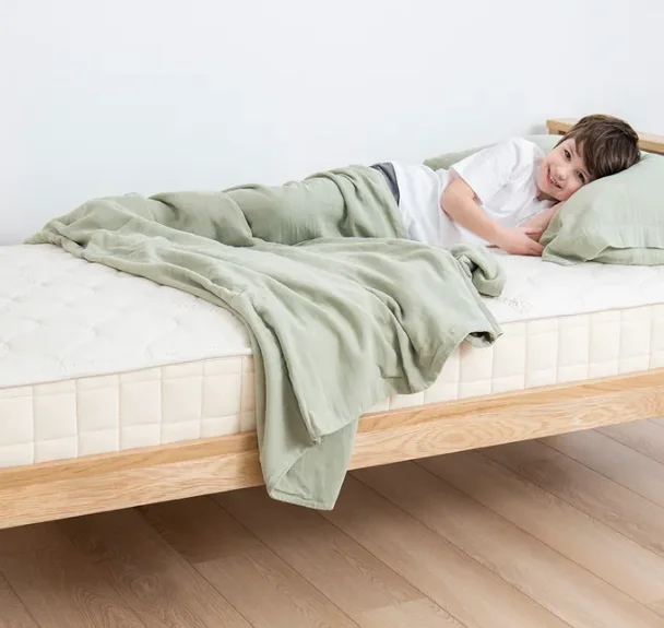 

Breathable Organic Cotton Muslin Kids Blanket Elegantly folded at the end of their be