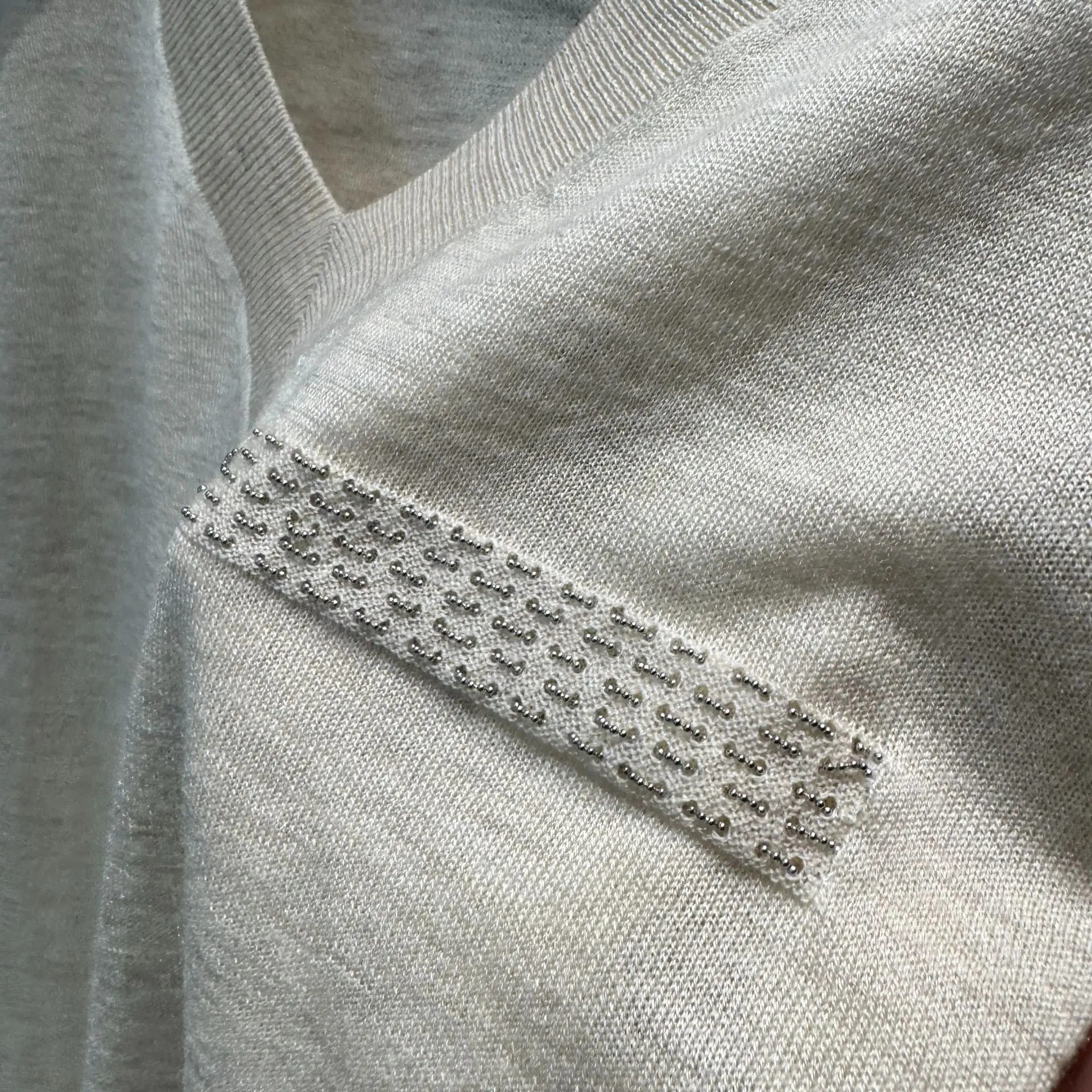 

Новая коллекция Весна/Лето 2026: Шелково-кашемировая вязаная футболка с V-образным вырезом и цепочкой на груди, свободный крой, стройнящий эффект