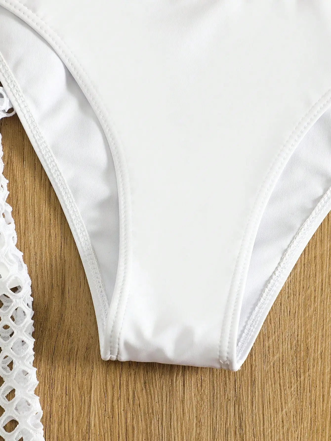 

Белый однотонный женский комплект бикини с завязками на шее, кружевной отделкой, треугольными плавками и прозрачной накидкой.