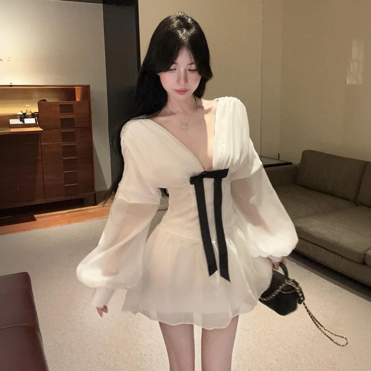 เดรสสั้นสีขาวแบบเซ็กซี่สไตล์ฝรั่งเศส คอวีลึก แต่งโบว์ แขนยาวทรงโคมไฟ ผ้าบาง โชว์เอวเข้ารูป ทรงเอไลน์ เหมาะสำหรับงานวันเกิด