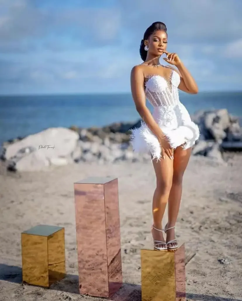 ชุดแต่งงานทรงเมอร์เมดแบบซีทรูประดับมุกสไตล์แอฟริกัน คอซีทรูแบบสั่งทำพิเศษ พร้อมขนนกสั้นสำหรับเจ้าสาว ชุดแต่งงานชายหาด