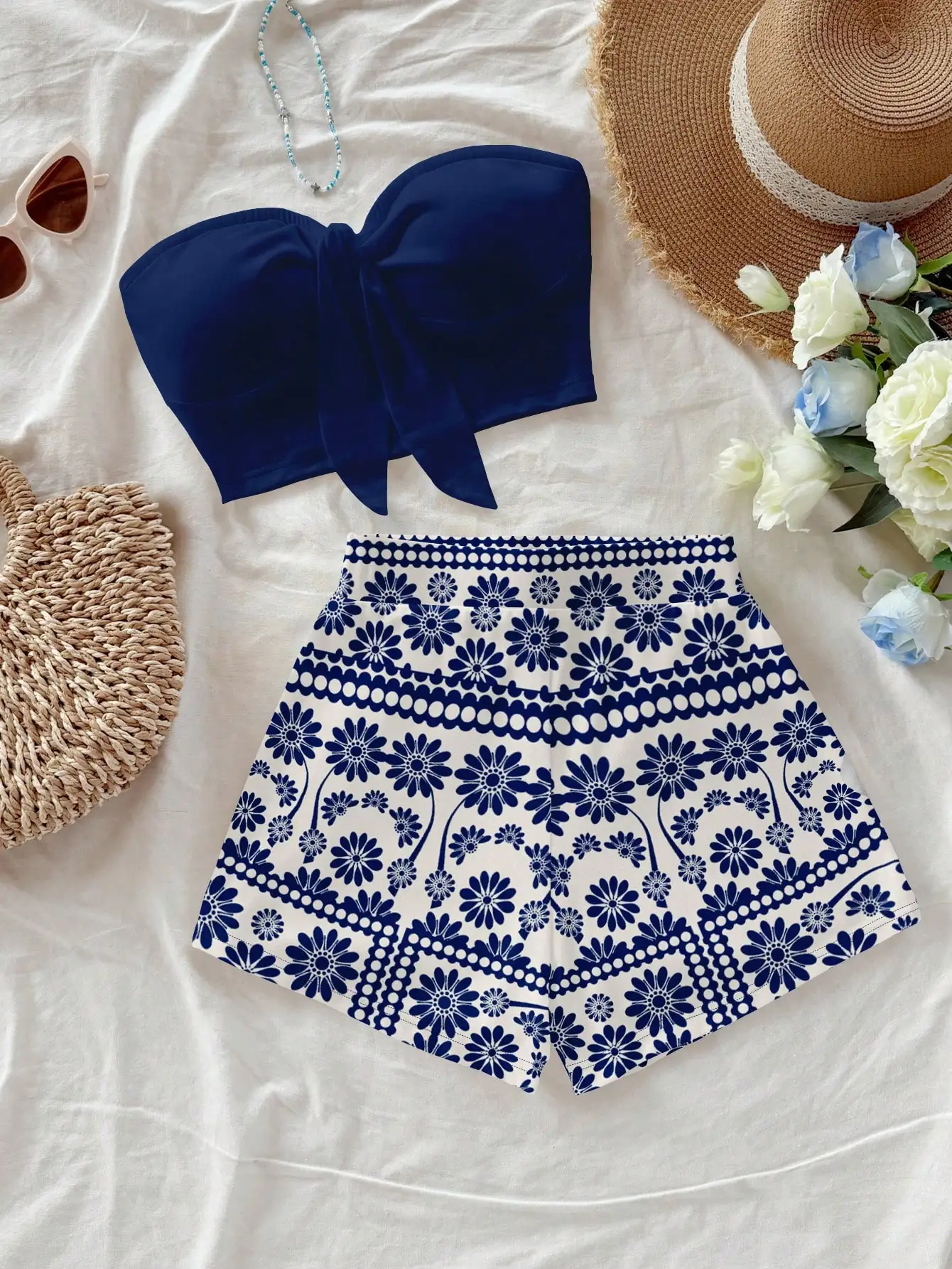 

Женский комплект из 2 предметов: топ-бандо с завязками темно-синего цвета и белые шорты с сине-белым цветочным принтом