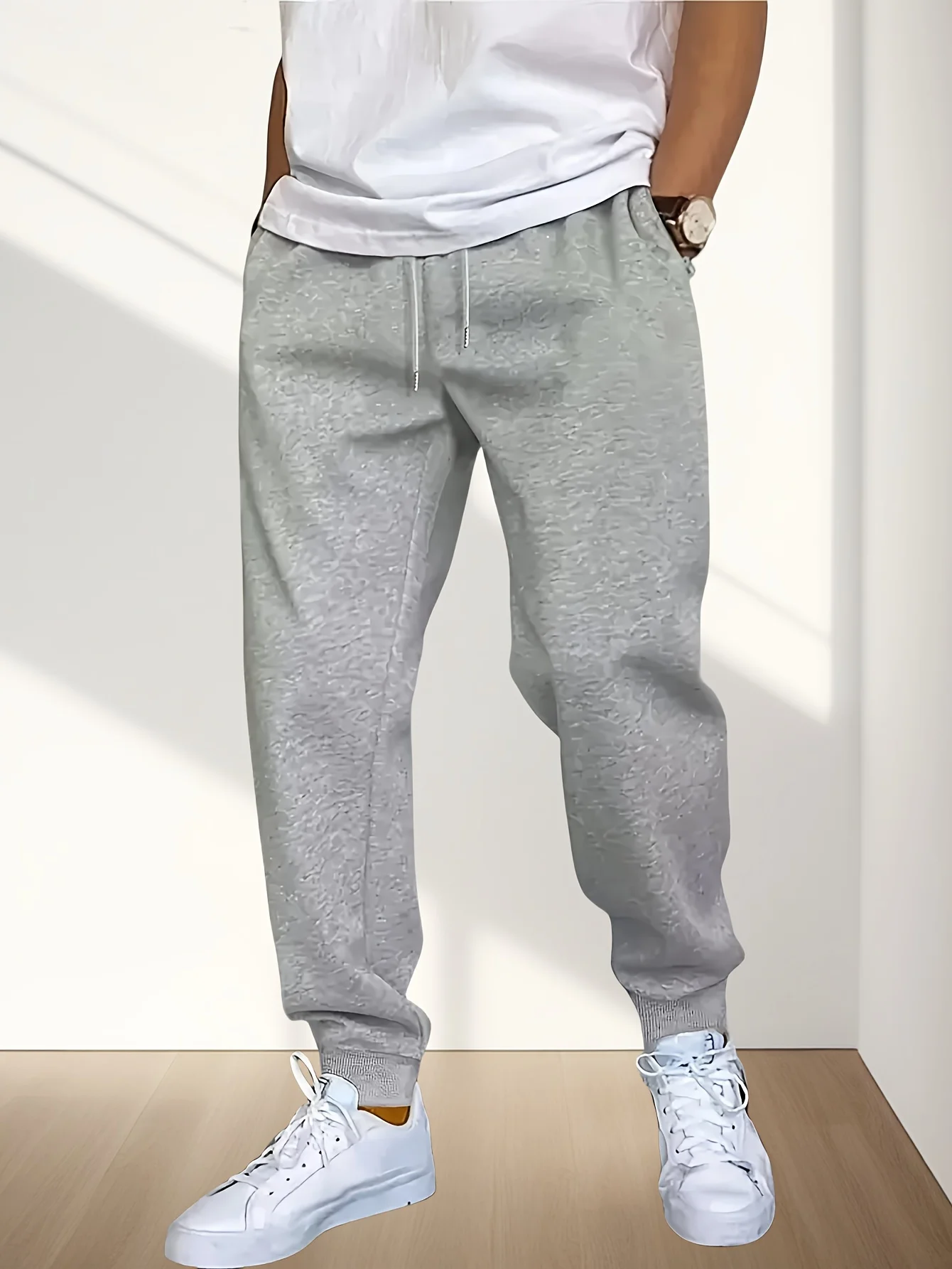 Calça de moletom casual masculina cinza folgada com punhos enrolados no tornozelo e cintura com cordão, adequada para todas as estações.