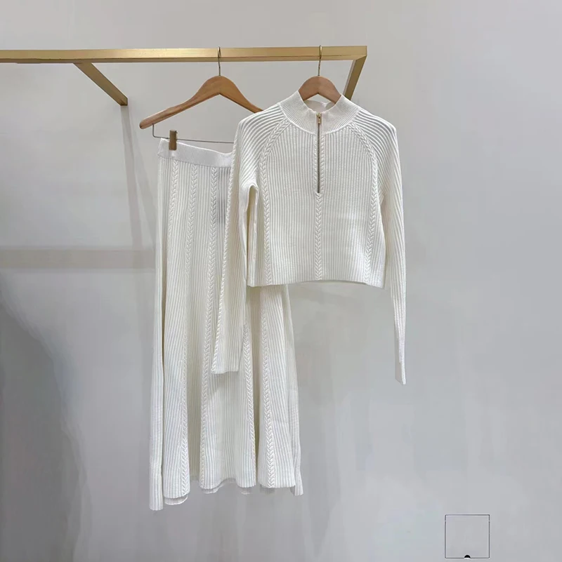 

Модный женский вязаный комплект на осень 2025: топ с цветочным узором, круглым вырезом и молнией, а также юбка-солнце средней длины с длинными рукавами