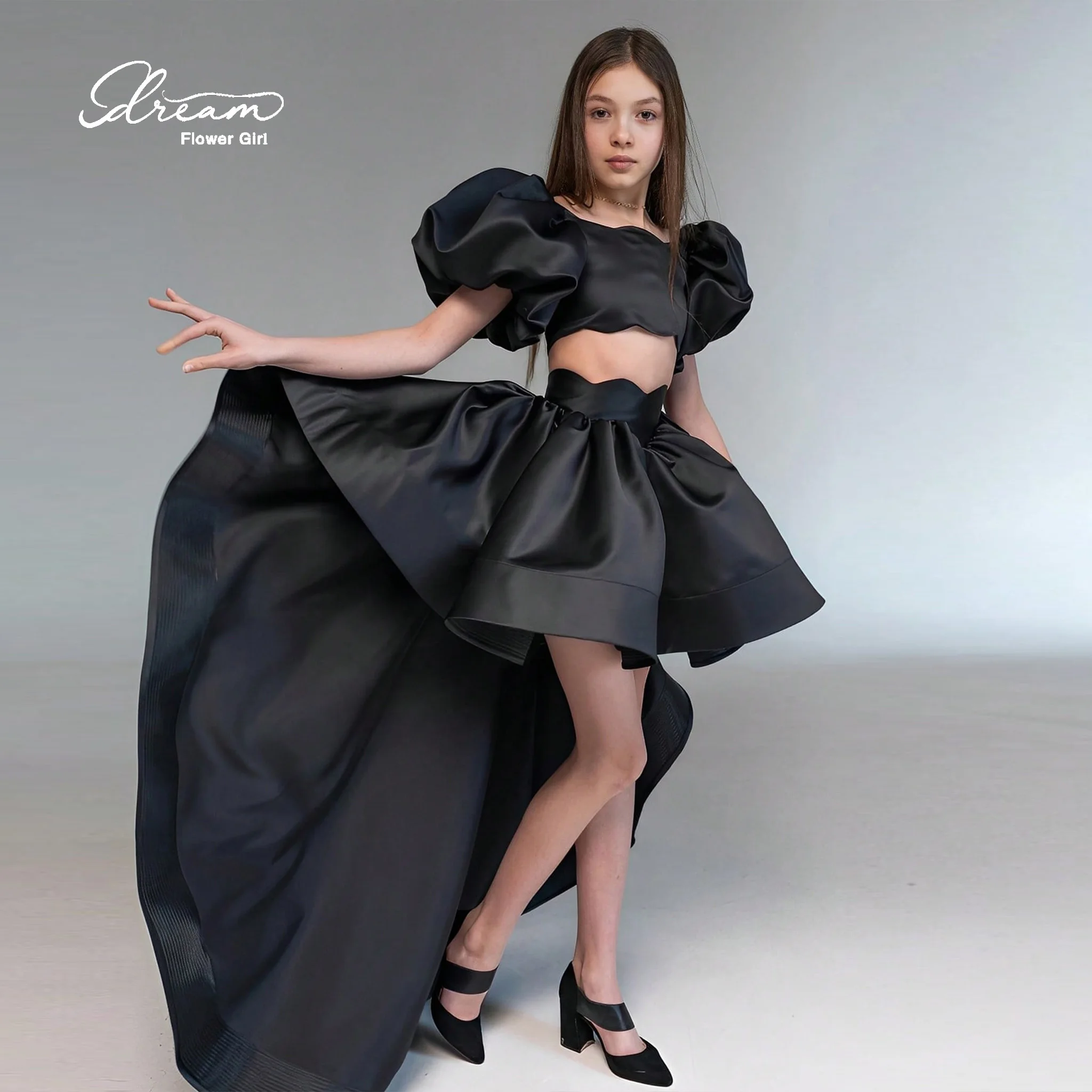Girls' formal ball gown featuring a black flat collar cape sleeves a voluminous skirt a cut-out waist and an asymmetrical he