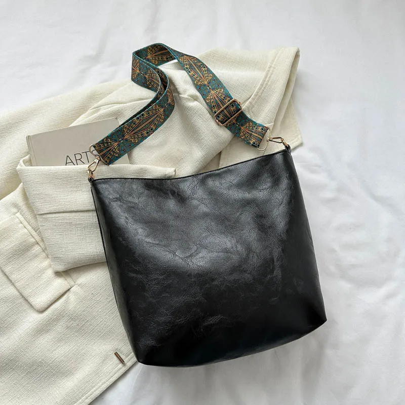 Sac tendance 2025 A/W avec une large sangle. Cuir souple, spacieux et rétro-chique pour un transport élégant et confortable.