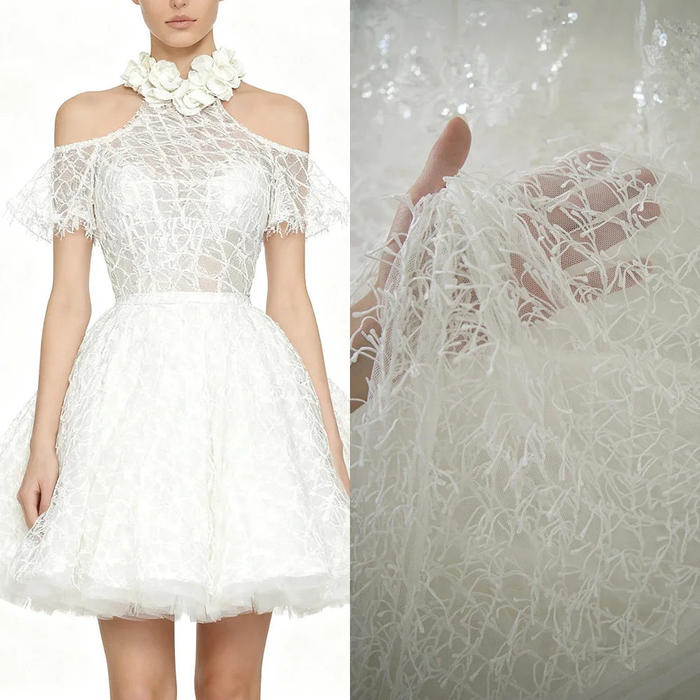 Weißer Spitzenstoff mit Fransen und der strukturierte, netzähnliche Stoff für Hochzeitskleider und formelle Kleider