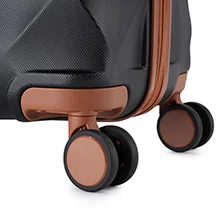 Close-up of luggage wheels, showing black and copper-colored spinner wheels attached to a dark-colored suitcase base.