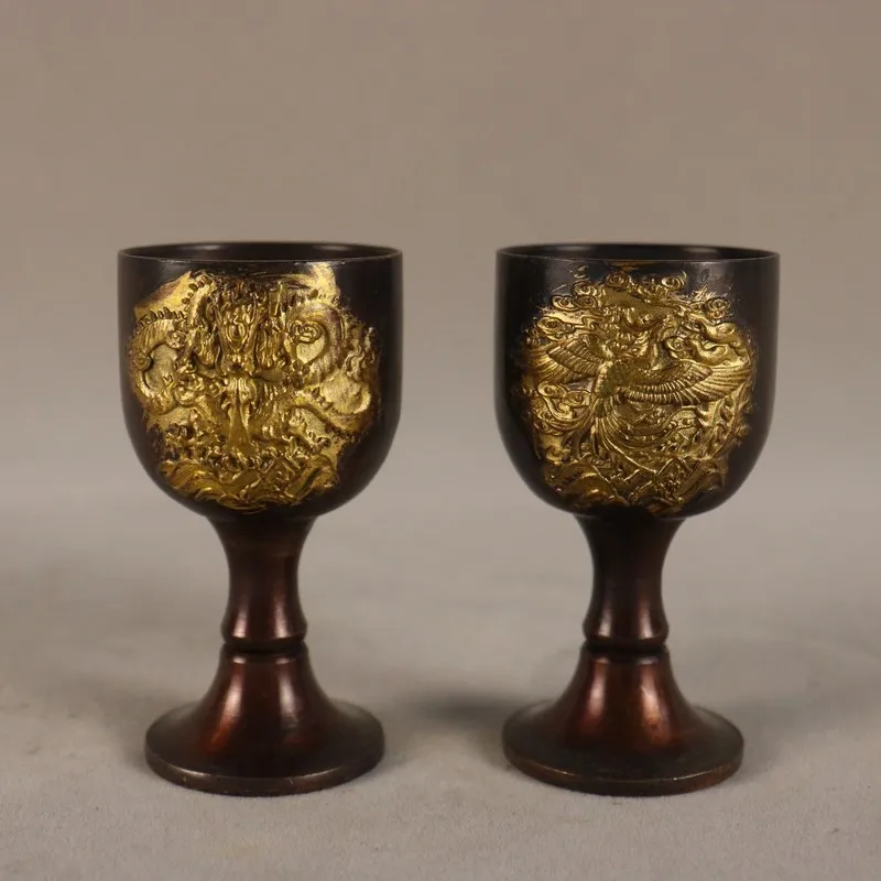 A pair of antique brass goblets with gilded dragon phoenix motifs, a set of wine glasses and decorative pieces