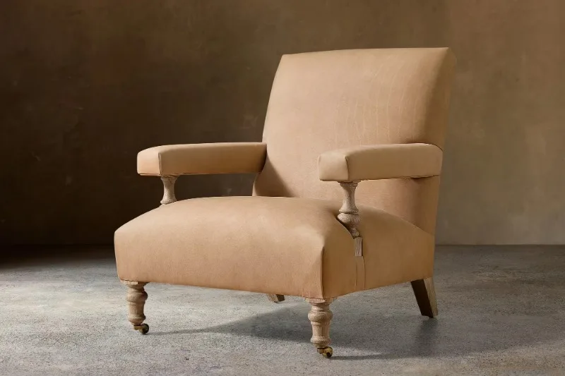 Leather-upholstered armchair with bleached oak legs and brass casters, country-style lounge chair for study villas