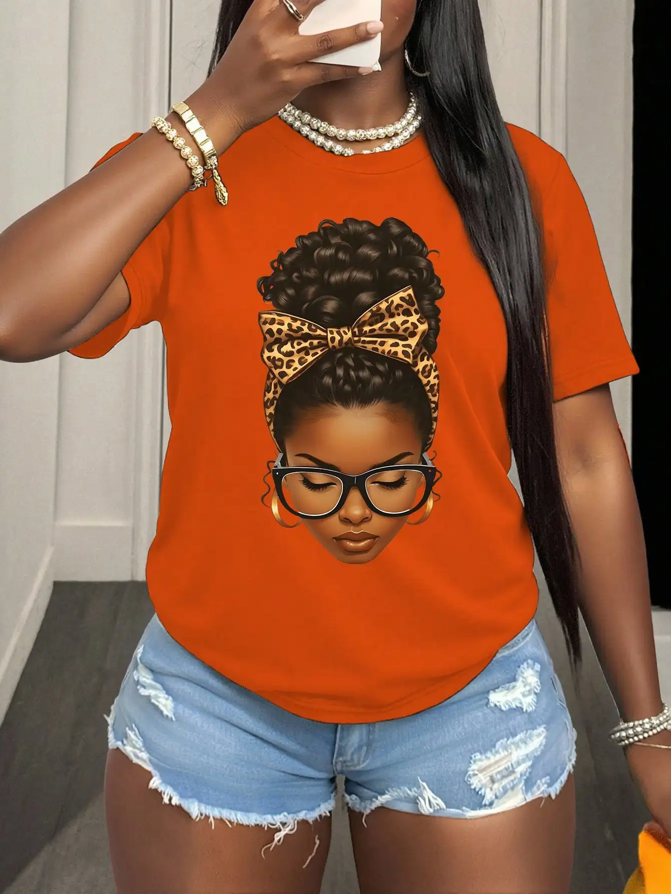 

Оранжевая футболка с круглым вырезом, короткими рукавами и графическим принтом, украшенная леопардовым бантом.