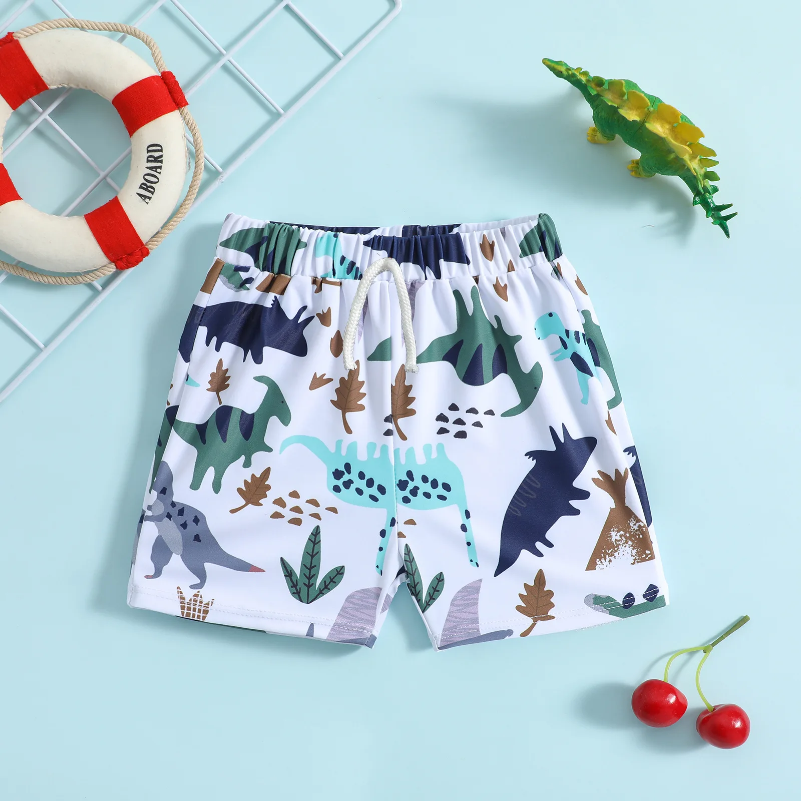 Boys drawstring swim shorts with cartoon dinosaur and plant print on white base suitable for seaside and pool play