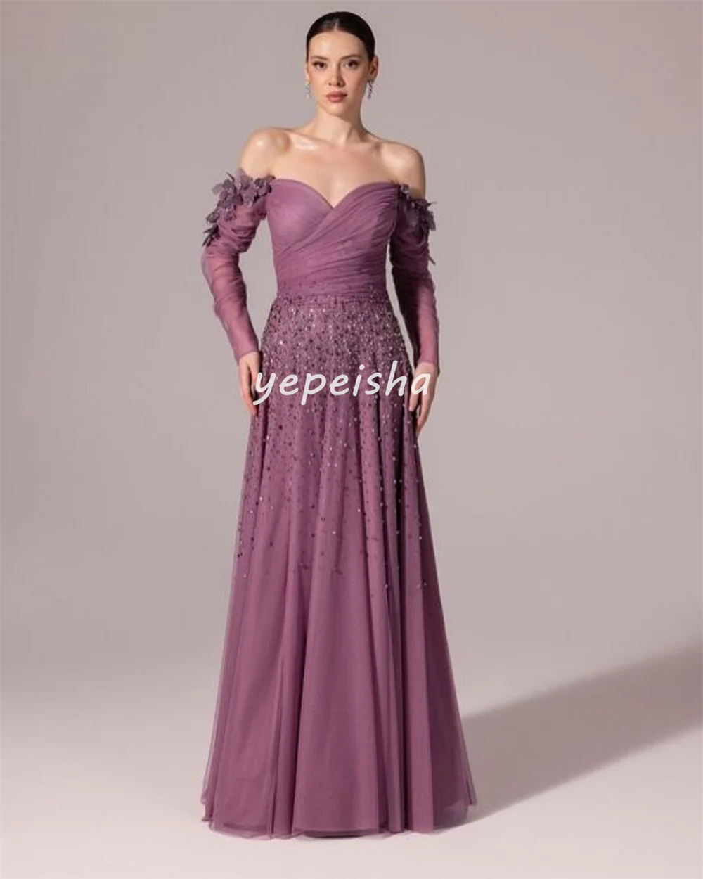 ชุดราตรีทรงเอไลน์แบบเปิดไหล่ ประดับด้วยผ้าทูลล์ระยิบระยับ แต่งดอกไม้ ลูกปัด และเลื่อม ดีไซน์หรูหรา