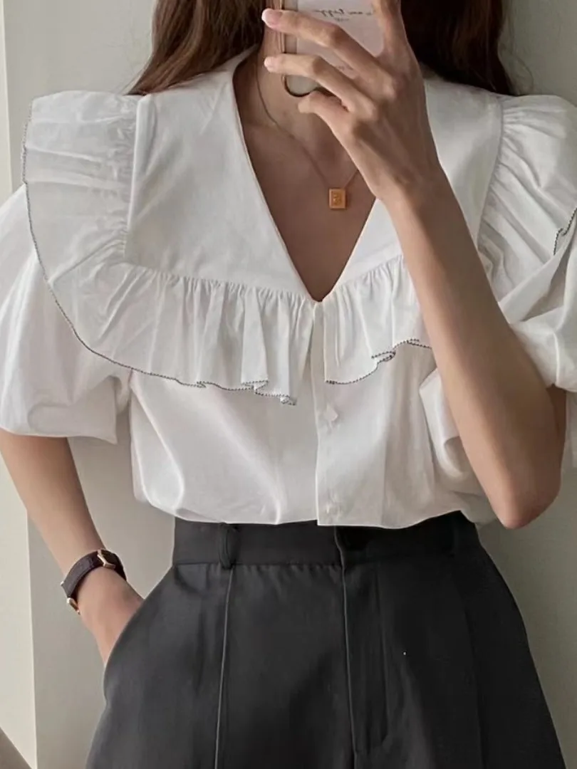 Csa fena e e simples com gola azul marinho, manga bufante com babados e botão único, estilo verão.