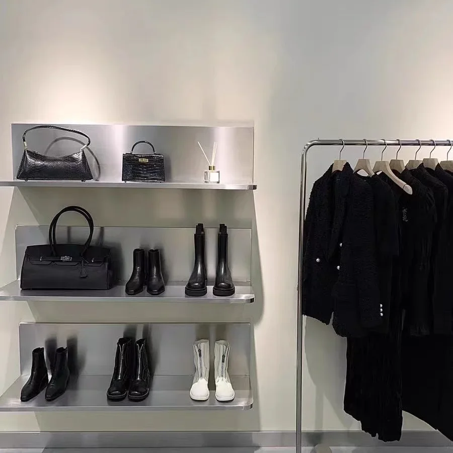 Tienda de ropa, zapatos, bolsos, estanterías de acero inoxidable, estanterías de zapatos de varias capas en la pared, estanterías de exhibición en el área de ventas.