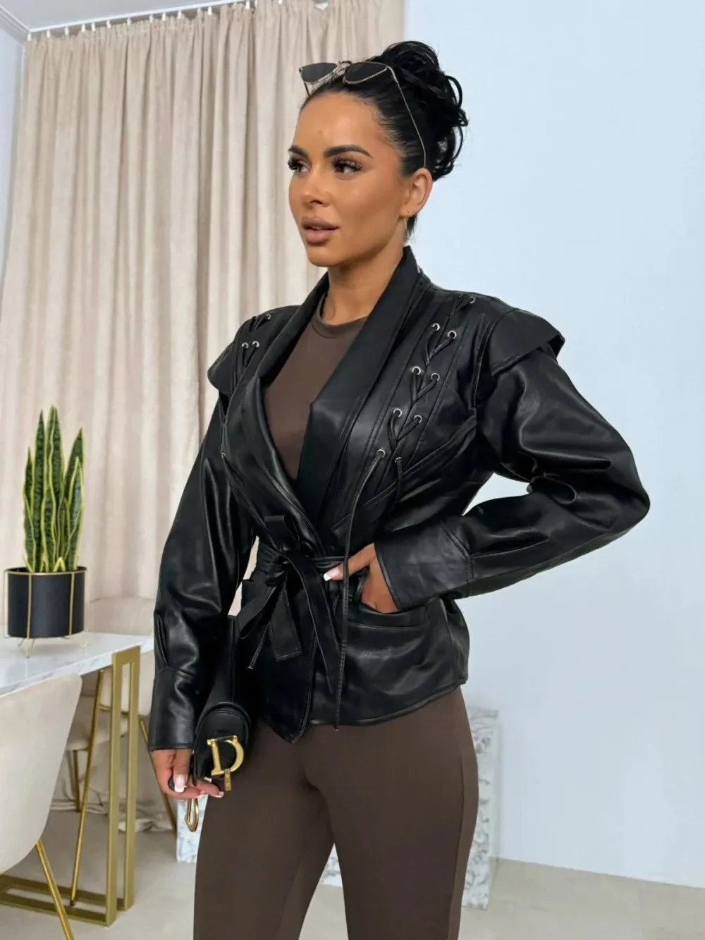 Krótka skórzana kurtka damska sznurowana, dopasowany krój, dekolt w serek, podkreślająca talię, jesienna moda damska, casualowa odzież wierzchnia w stylu streetwear.