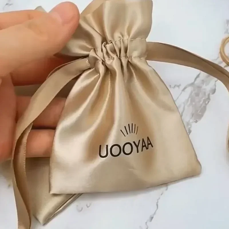 Konfigurowalne logo Złote satynowe torby na prezenty Kolczyki Pierścionki Szpilki Naszyjnik Bransoletka Biżuteria Muślinowe woreczki ze sznurkiem 9 * 12 cm 20 sztuk