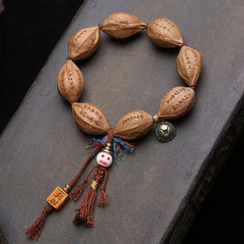 Hand-woven bracelet featuring natural olive pits engraved with the Heart Sutra, with copper clasps and recycled bone accents