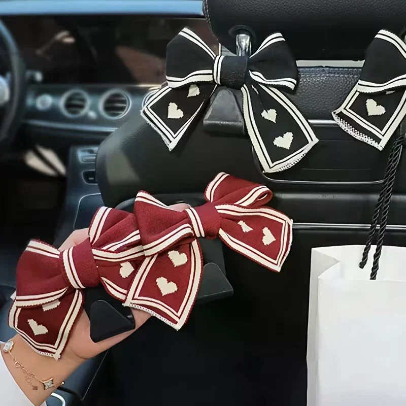 Two Car Seat Headrest Hooks With A Black And White Heart-shaped Bow Design; Universal Design Suitable For All Vehicles.