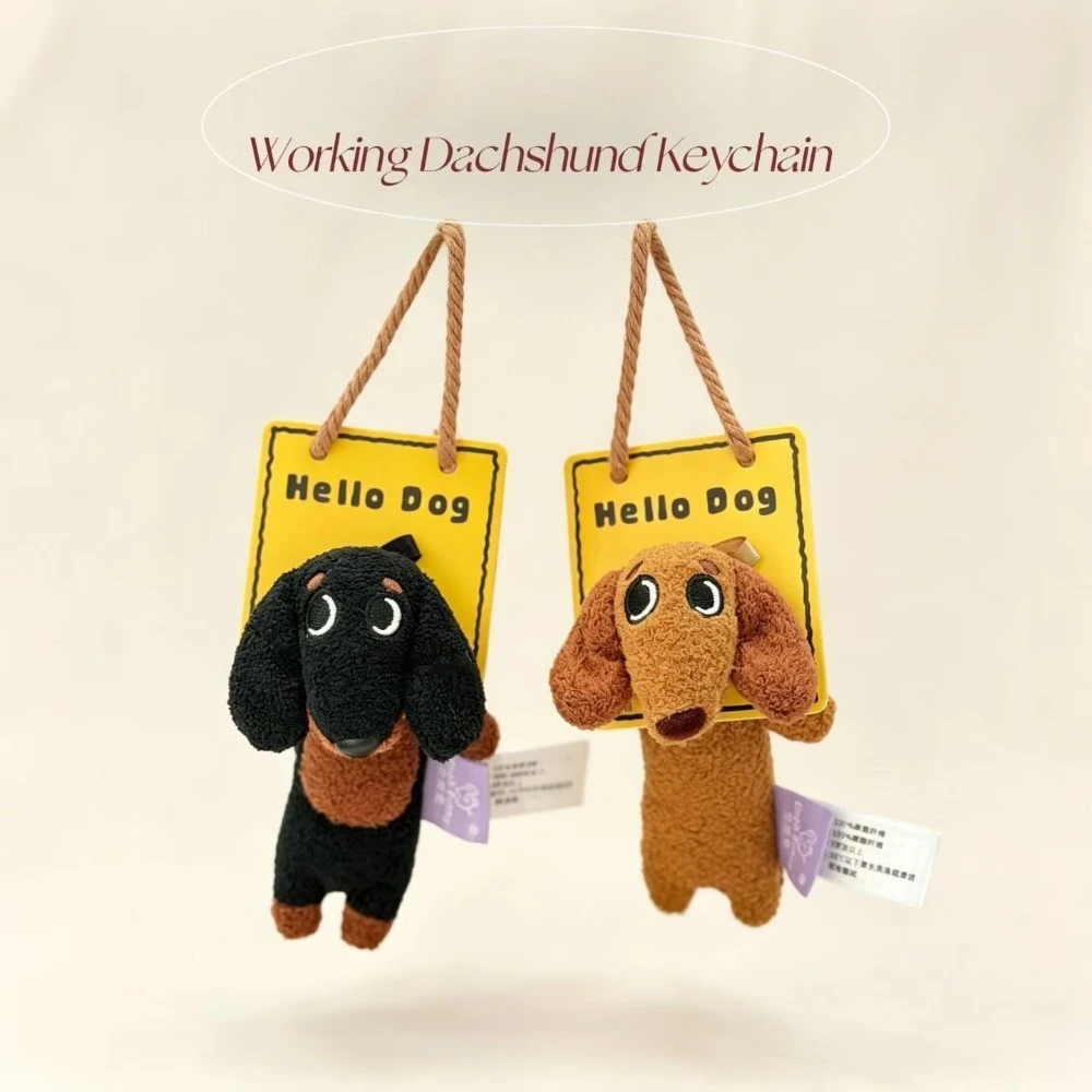 Two small plush dachshund charms in black and brown hanging from a card.