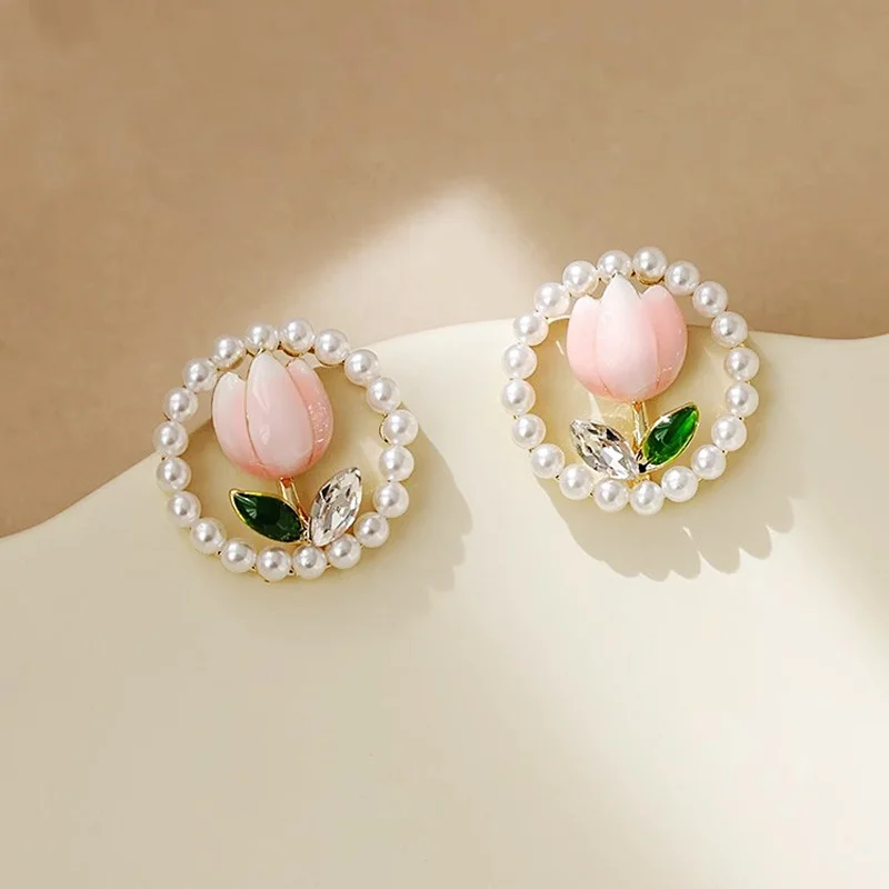A pair of elegant alloy floral earrings with acrylic pearls and green leaves, and stylish sparkling tulip studs, perfect as a bi