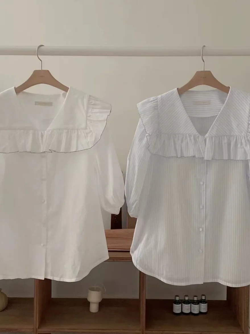 Csa fena e e simples com gola azul marinho, manga bufante com babados e botão único, estilo verão.