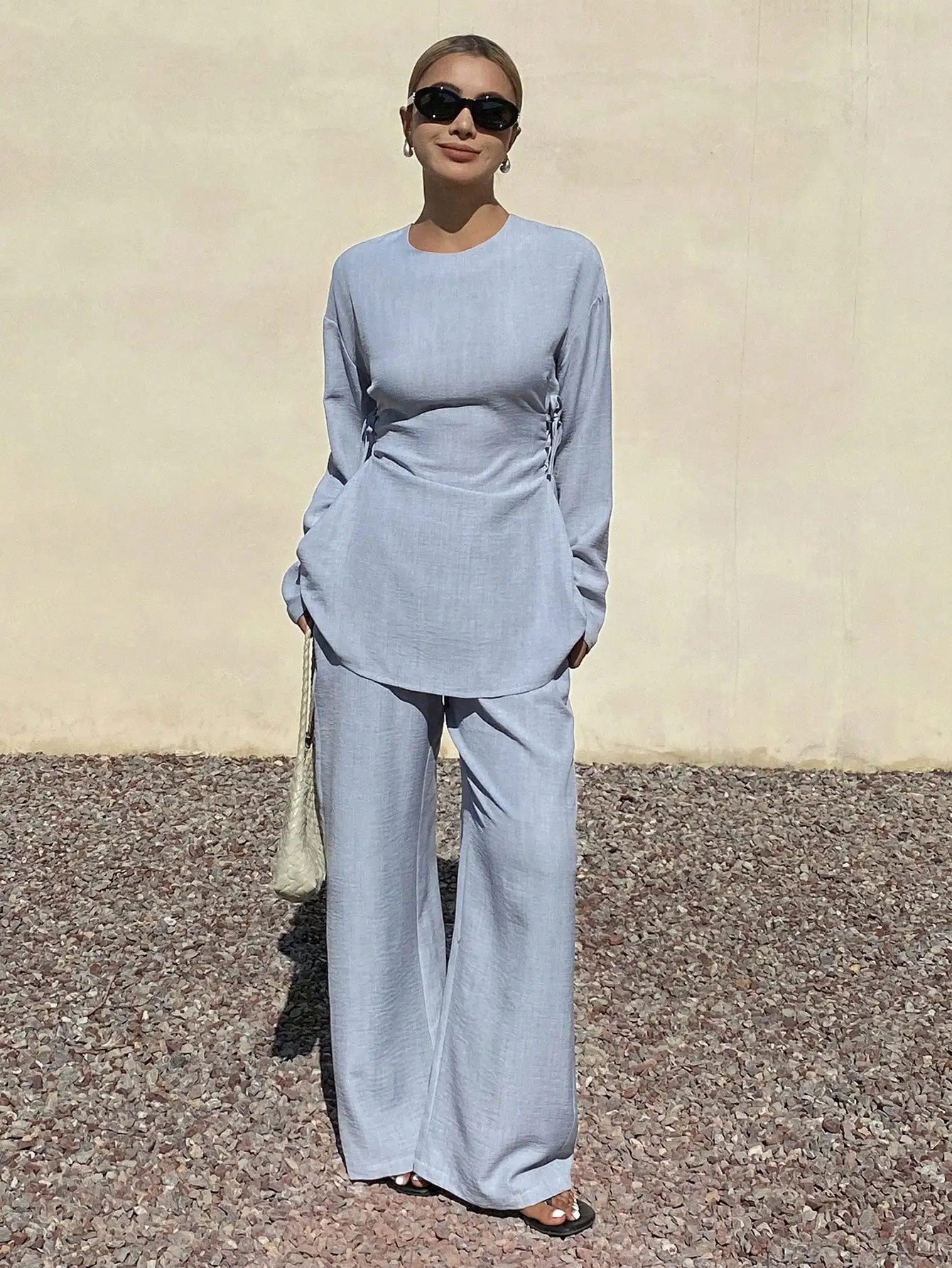 

Женский комплект из двух предметов: однотонный топ с круглым вырезом и длинными рукавами с эффектом складок и широкие брюки.