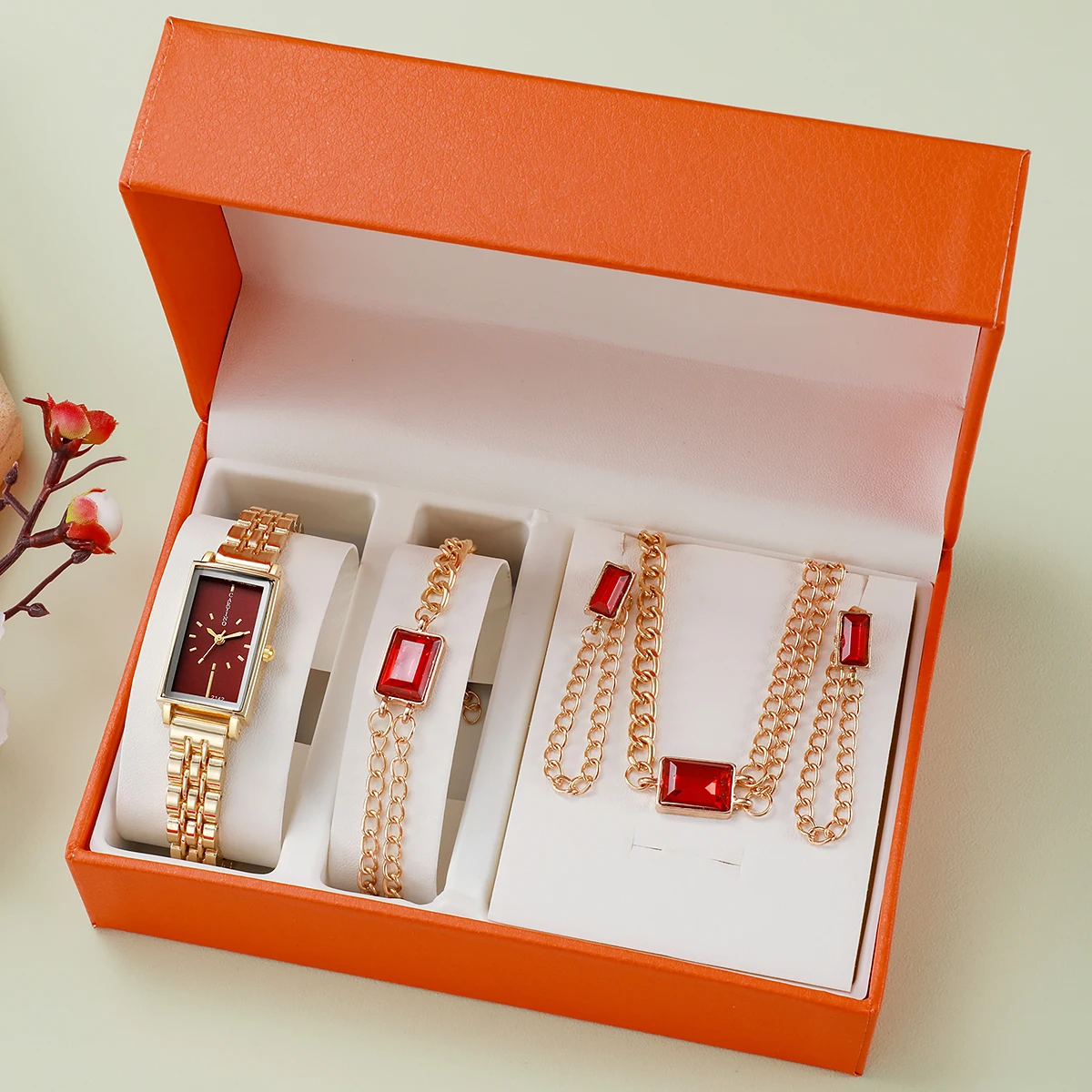 

Набор украшений: золотистые часы и украшения с красными камнями - прямоугольные часы с бордовым циферблатом, квадратный кулон с рубином, браслет и серьги-подвески.