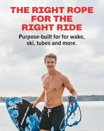 Young man holding an Airhead wakeboard and tow rope on a lakeside dock.