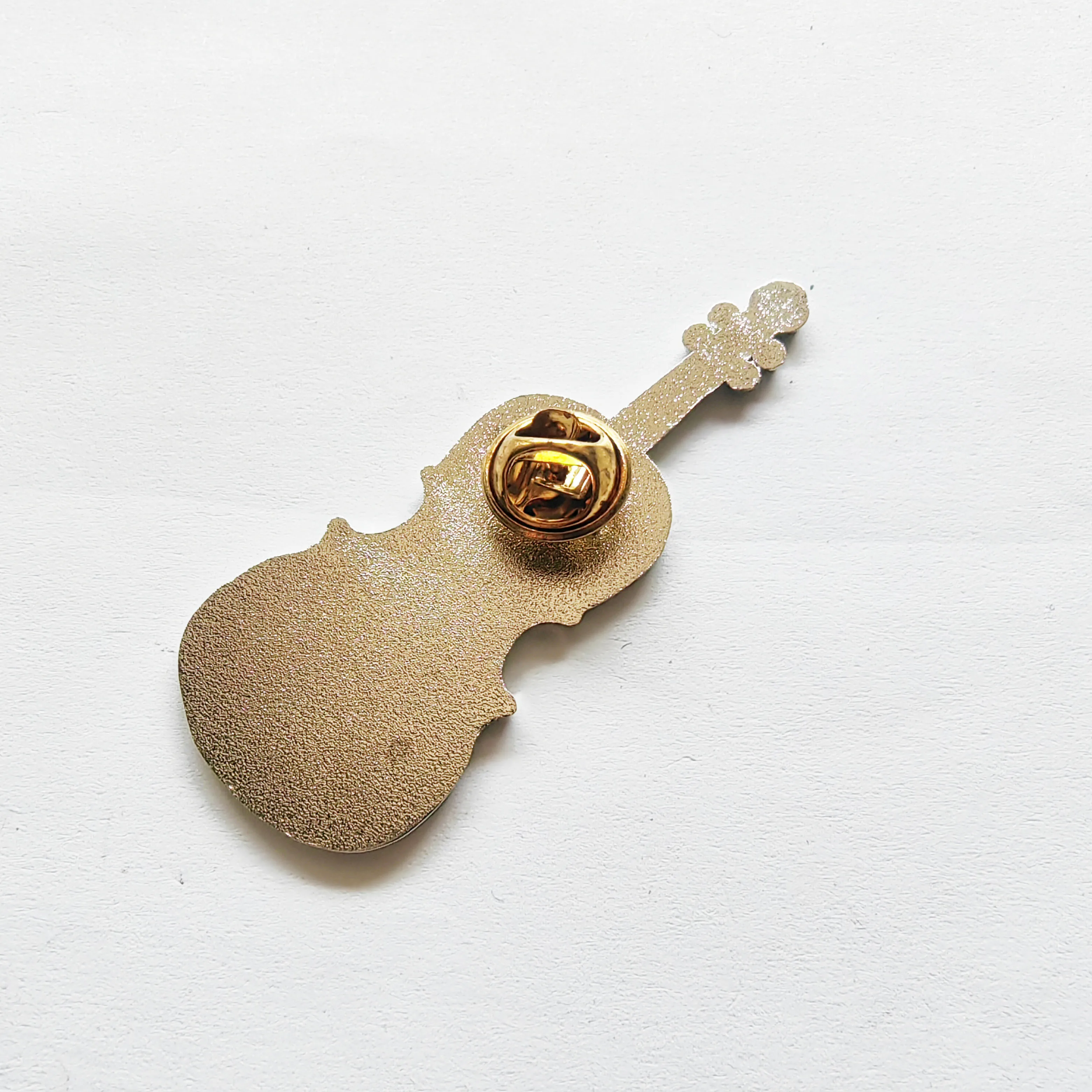 A metal badge representing a musical instrument