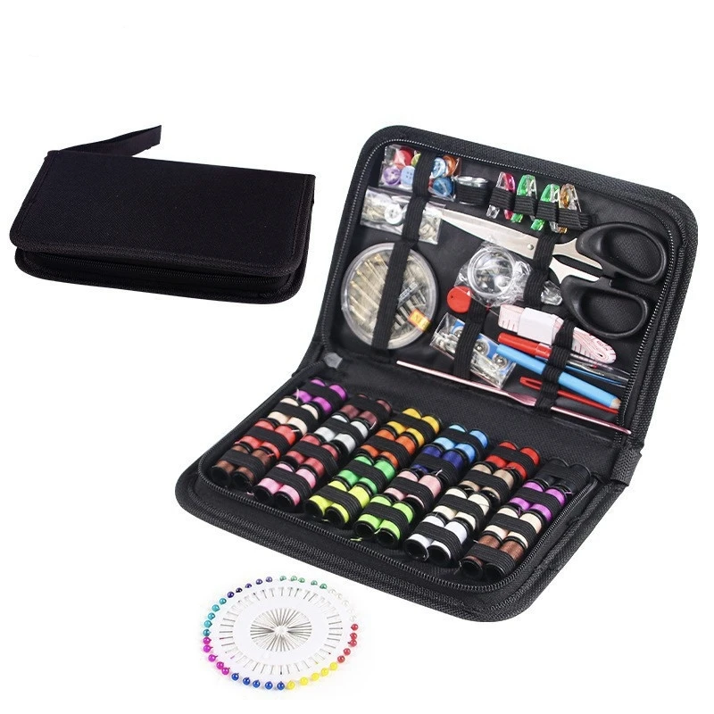 Open black sewing kit with various sewing supplies and its case on a light pink background,