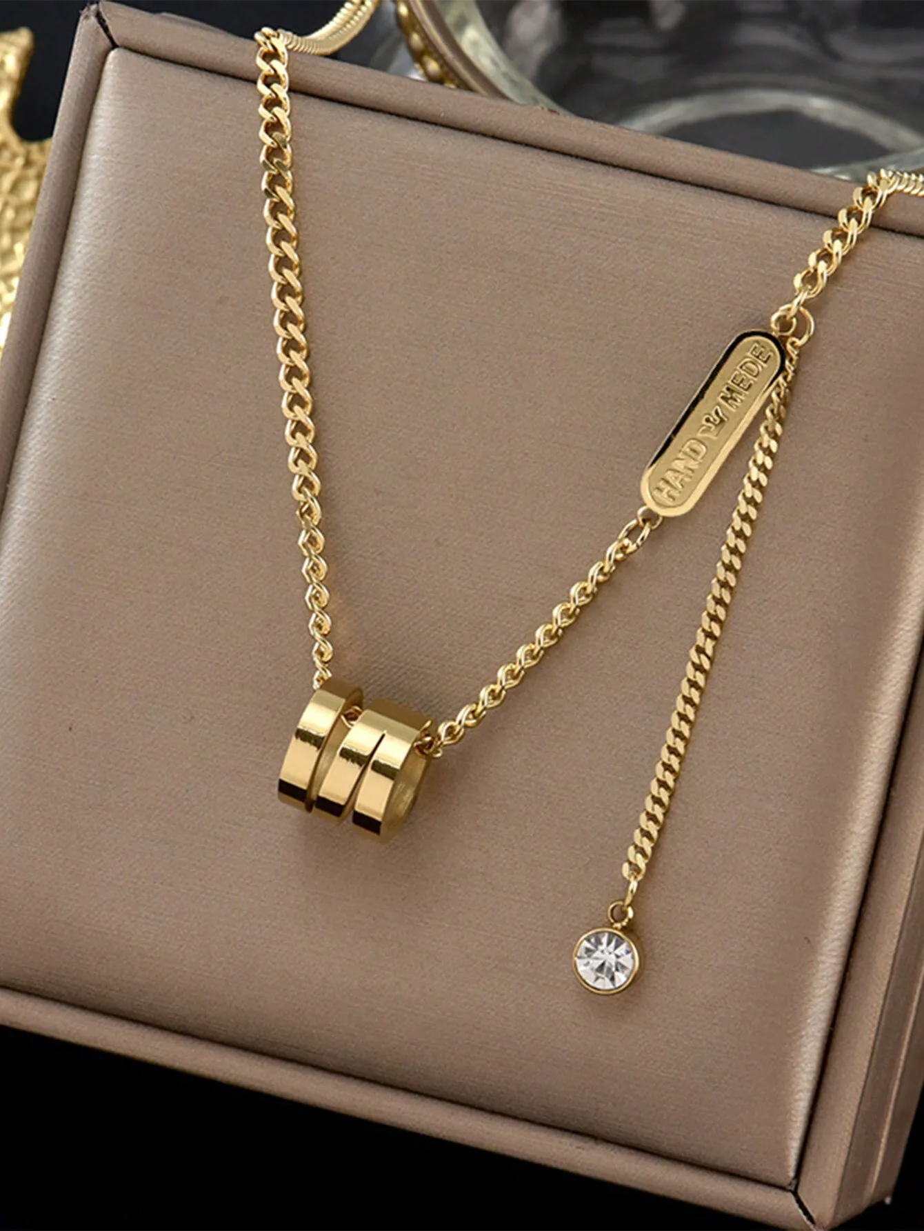 

Многослойное золотистое ожерелье-цепочка с подвеской в виде тройного кольца и кристаллическим шармом