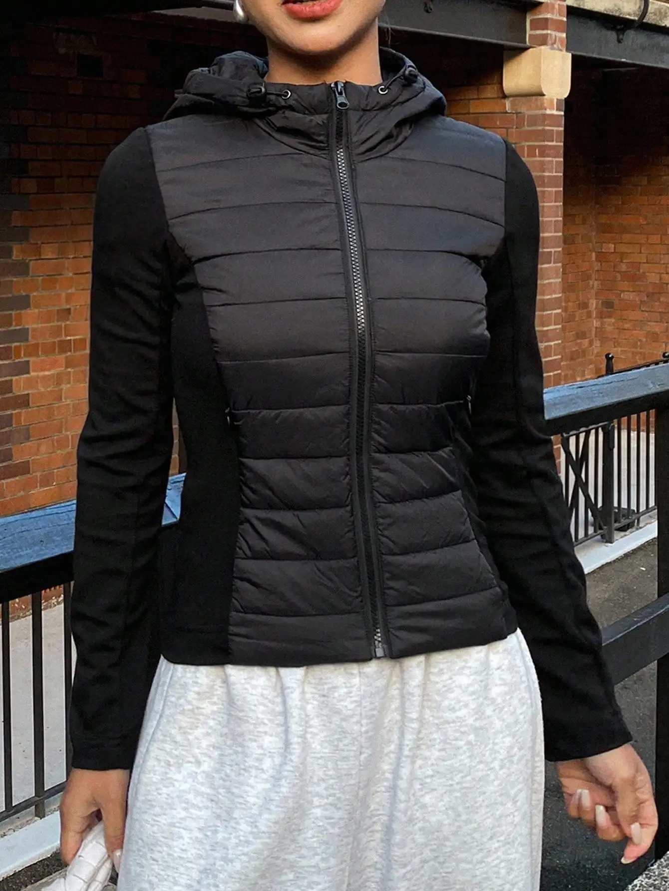 

Женская черная куртка-пуховик с капюшоном на молнии и контрастными вставками для осени и зимы