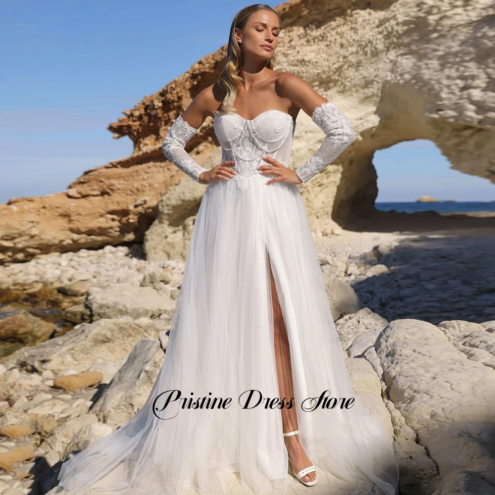 Suknia ślubna w stylu boho z odpinanymi rękawami, tiulowa, z rozcięciem z boku, sznurowana na plecach, dekolt w serce, zdobiona perłami, fason A-line, możliwość personalizacji.