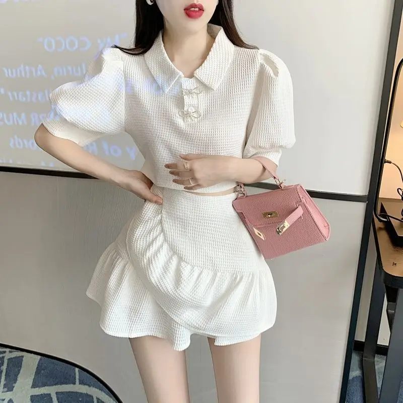 

Женский летний комплект из двух предметов: белая рубашка поло с пышными рукавами и юбка с оборками. Повседневный элегантный наряд из дышащей ткани. Новинка 2026 года.