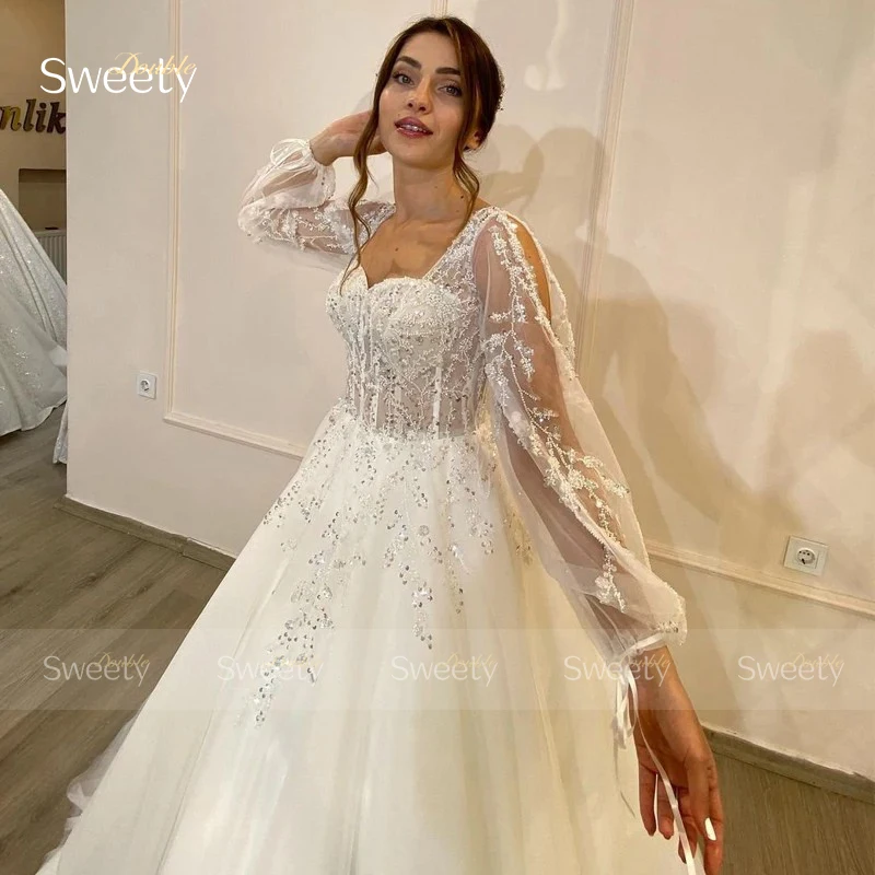 ชุดแต่งงานที่สง่างาม Organza เย็บปักถักร้อยประดับด้วยลูกปัด A-Line Ball Gown สแควร์คอแขนยาวชุดเจ้าสาวปุ่มที่กําหนดเอง