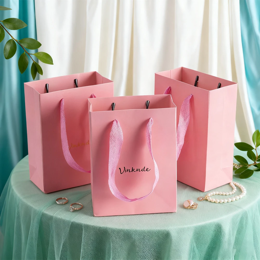 

Роскошная розовая картонная сумка для покупок с ручкой из ленты на заказ, бумажные сумки-тоут с индивидуальным принтом логотипа для ювелирных изделий, духов